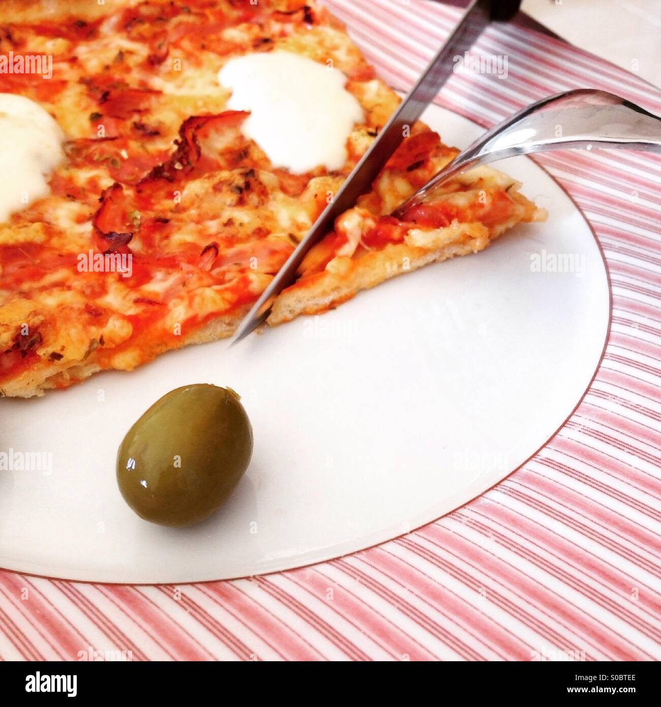 Slice of pizza with green olive on plate Stock Photo