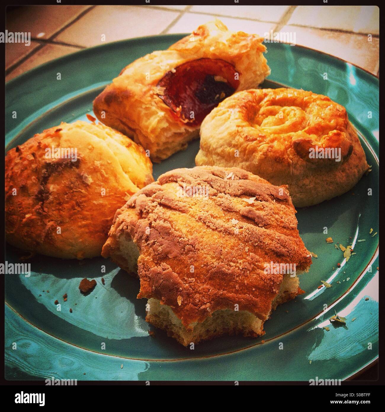 Pastries on a plate with one having multiple bytes around the edges Stock Photo
