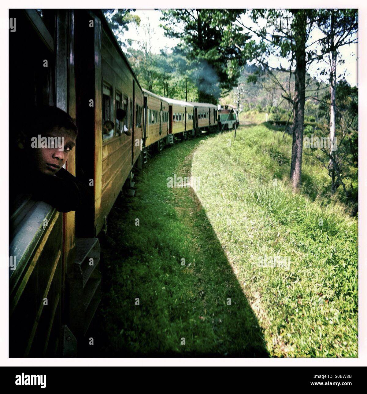 Boy looking out of the window of a train in Sri Lanka - Smartphone Captured Stock Image