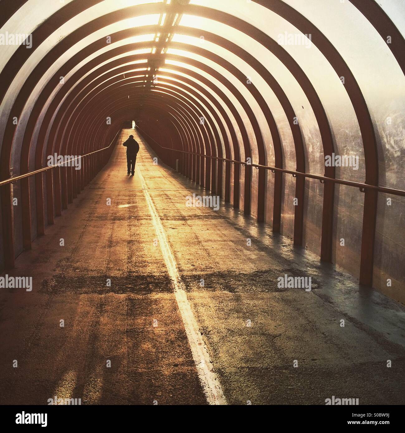 A silhouette of a man walking down a tunnel at sunrise in Glasgow Stock Photo