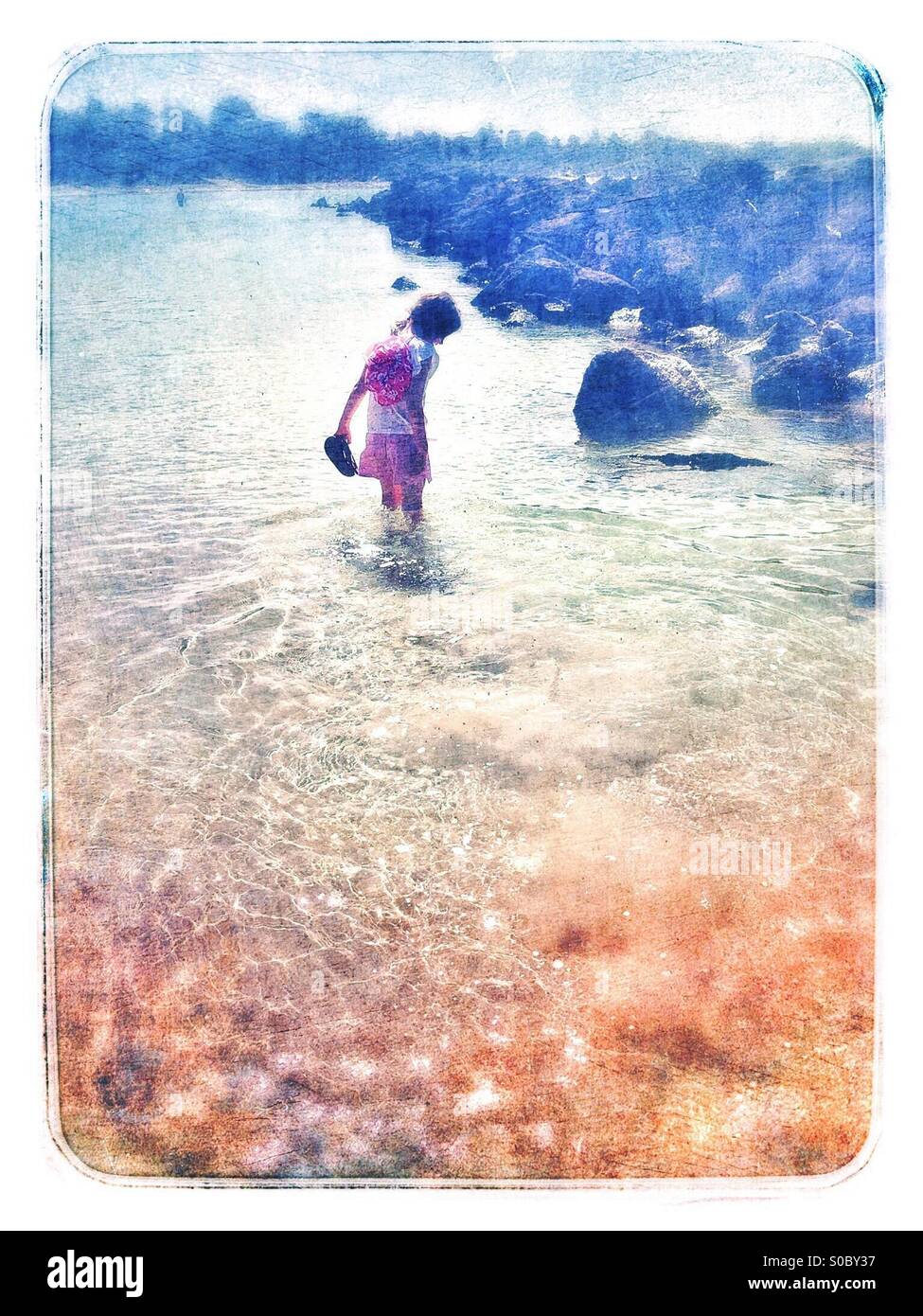 Summer dreaming - girl exploring shallows at the beach Stock Photo