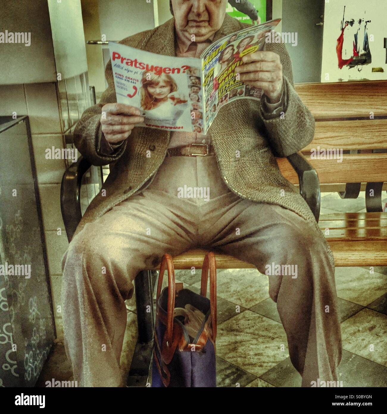 Old man reading gossip tabloid Stock Photo