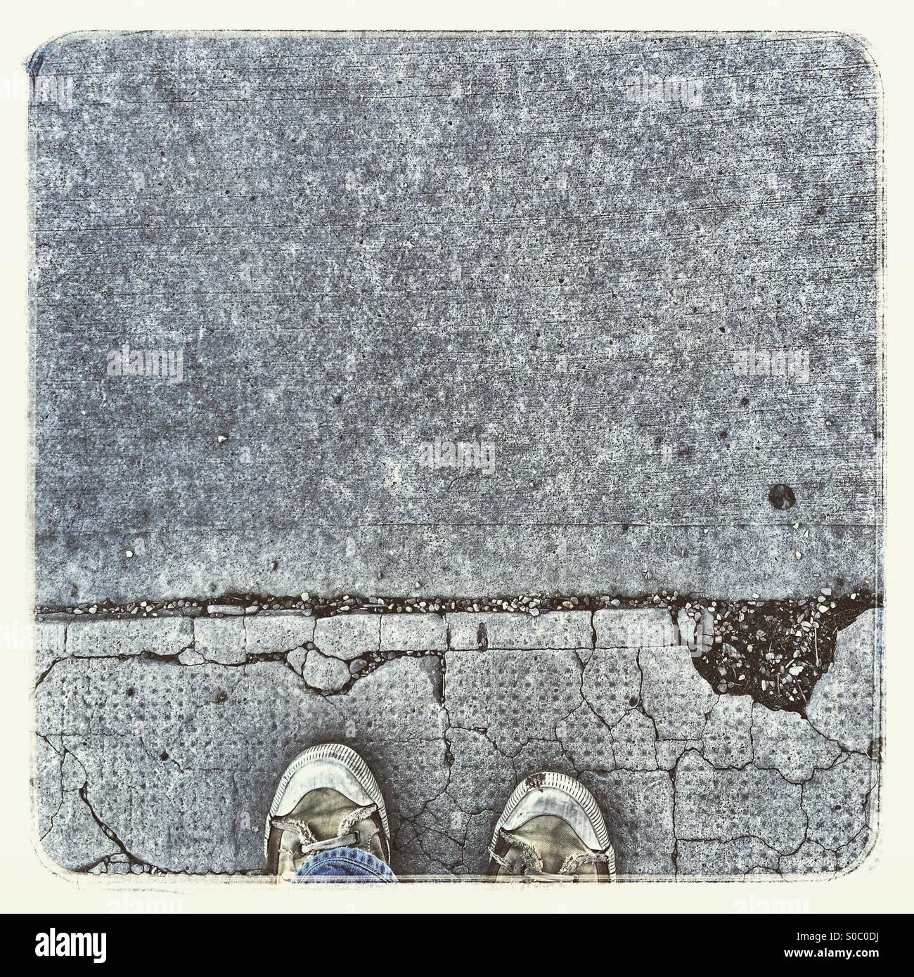 Bird's eye view of sneakers on cracked sidewalk. - Smartphone Captured Stock Image