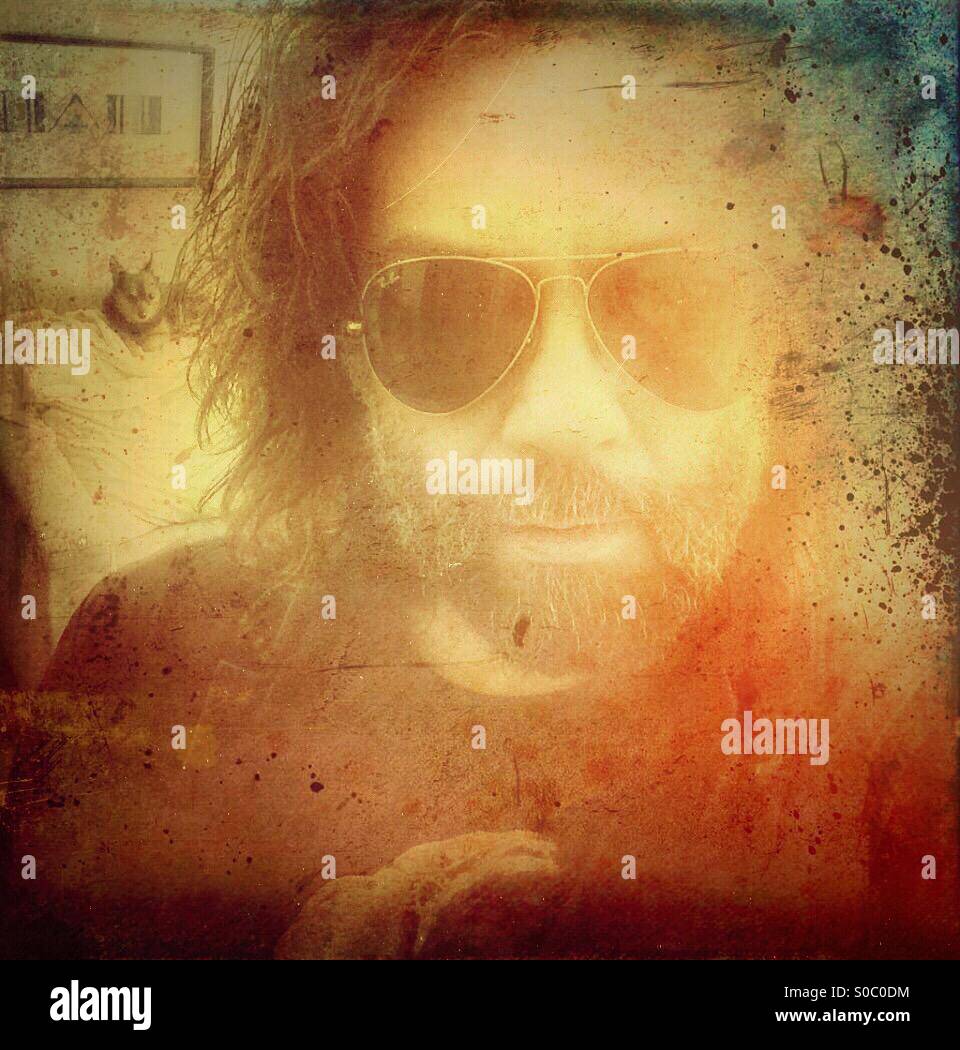 Bearded man in sunglasses with dog in background. - Smartphone Captured Stock Image