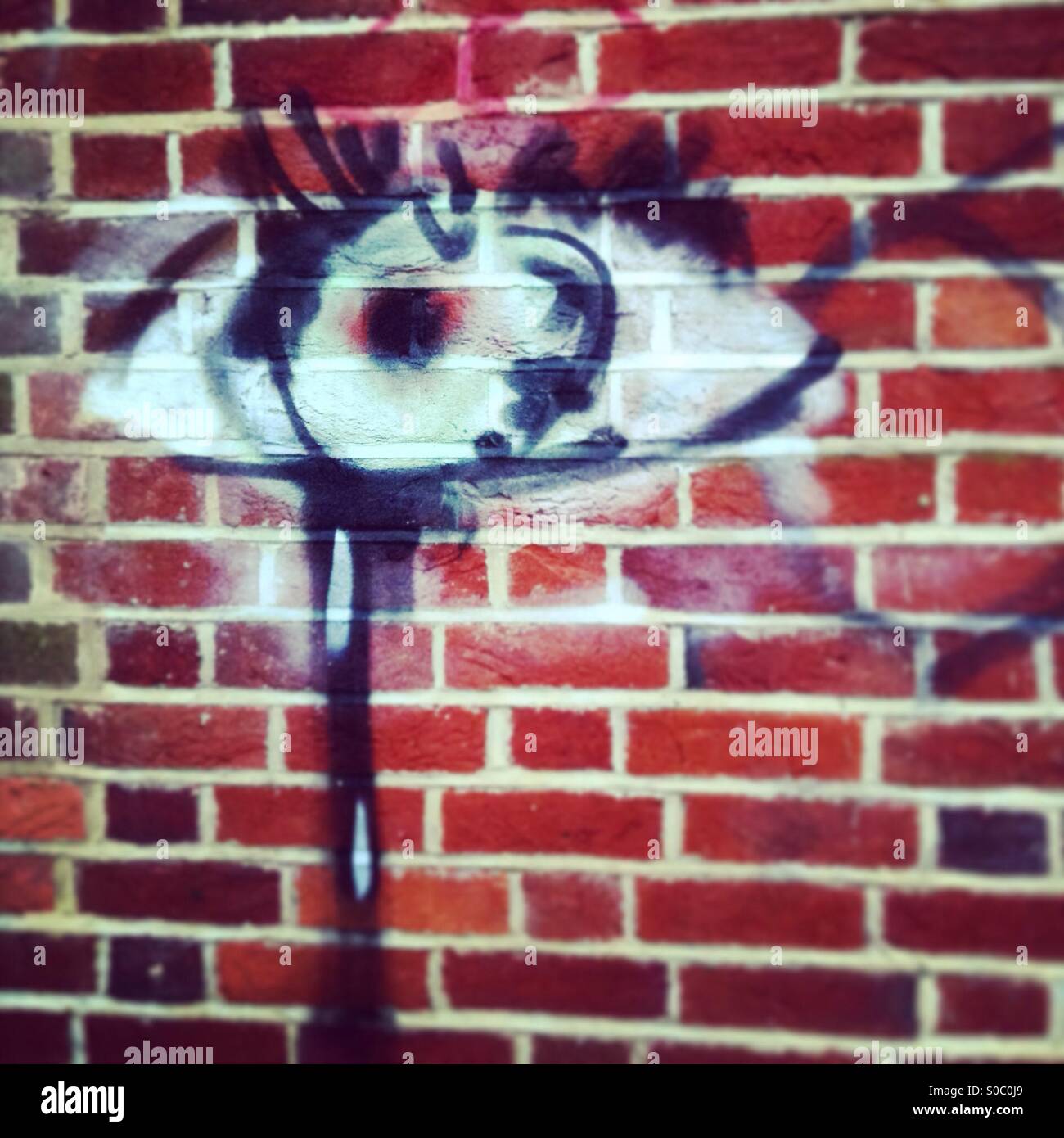 Eye and tears painted on brickwall Stock Photo