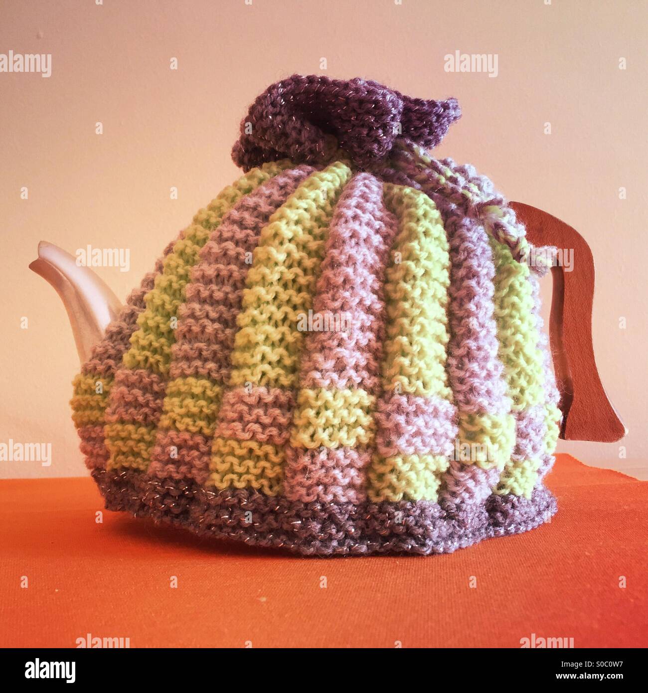Handmade knitted tea cosy on a stainless steel teapot Stock Photo