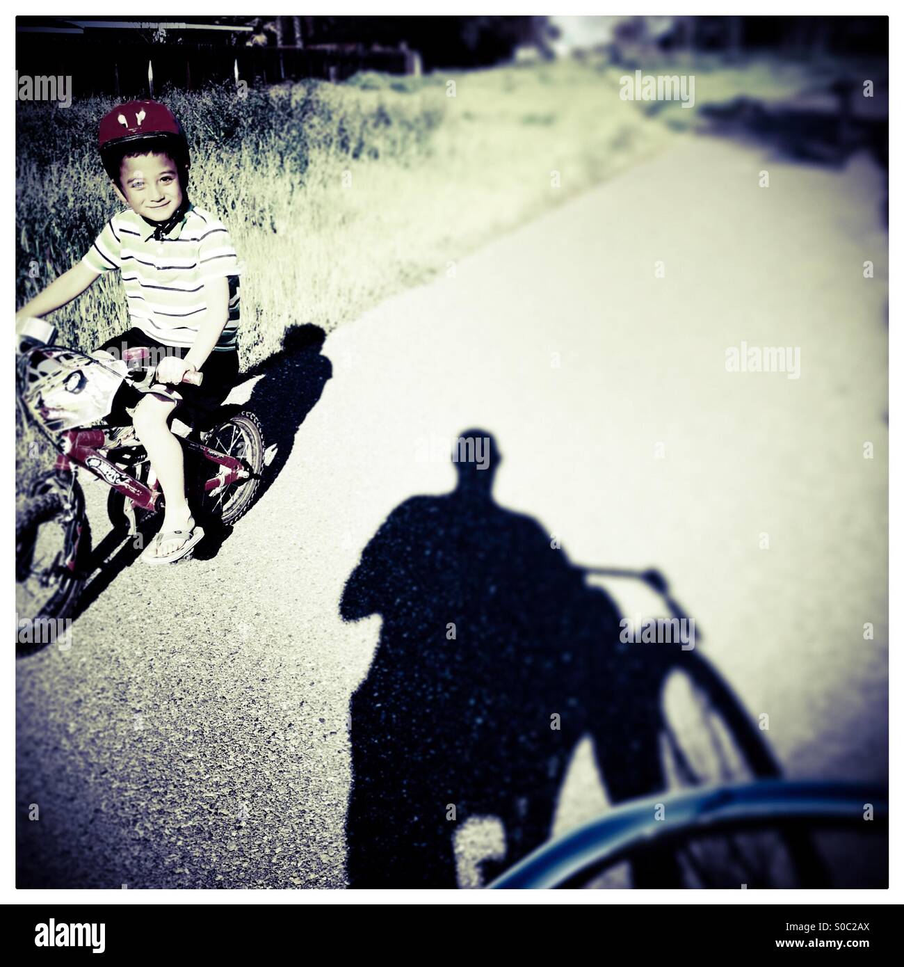 A seven year old boy rides his bike past a man on a bike path. Stock Photo