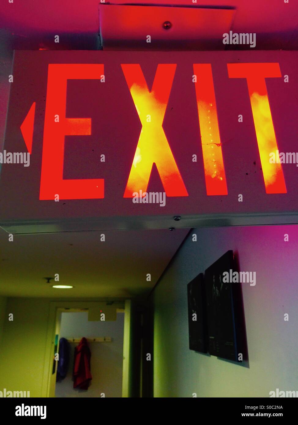 Well-lit Exit Sign in official colours. Glowing in orange and red. In use. Vertical. Copy space. - Smartphone Captured Stock Image