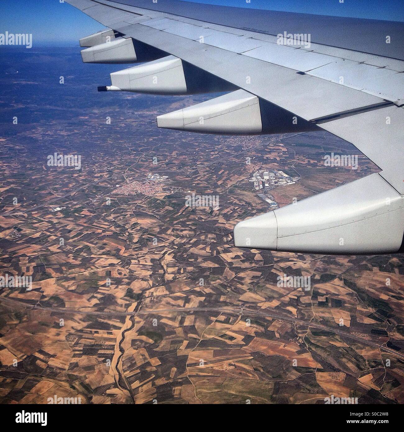 A plane flies over the arid and deforested land of Madrid, Spain - Smartphone Captured Stock Image