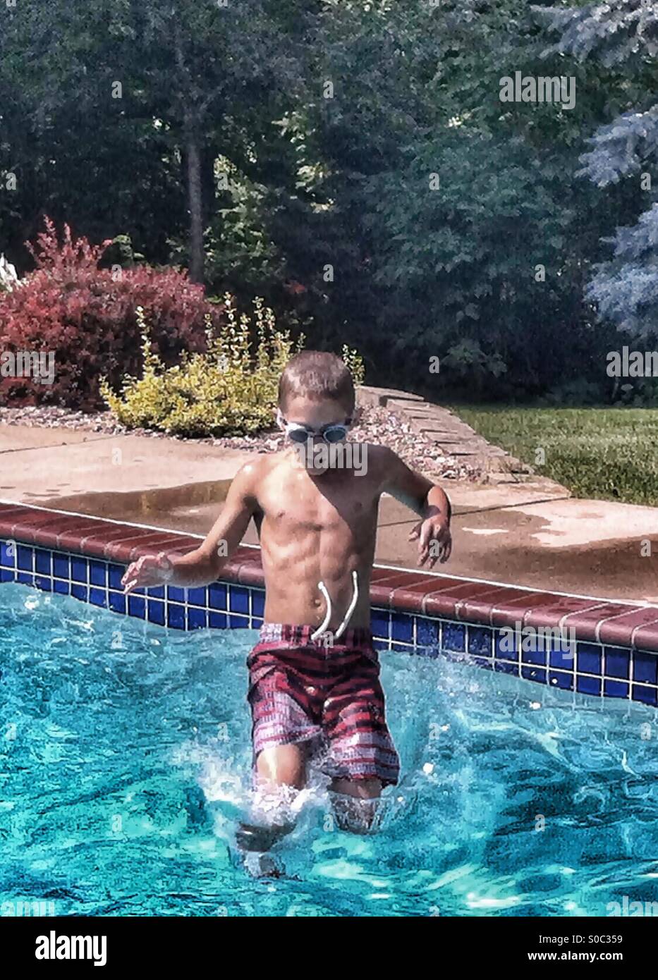 Young Boy Jumps Feet First into a Swimming Pool Stock Photo Alamy
