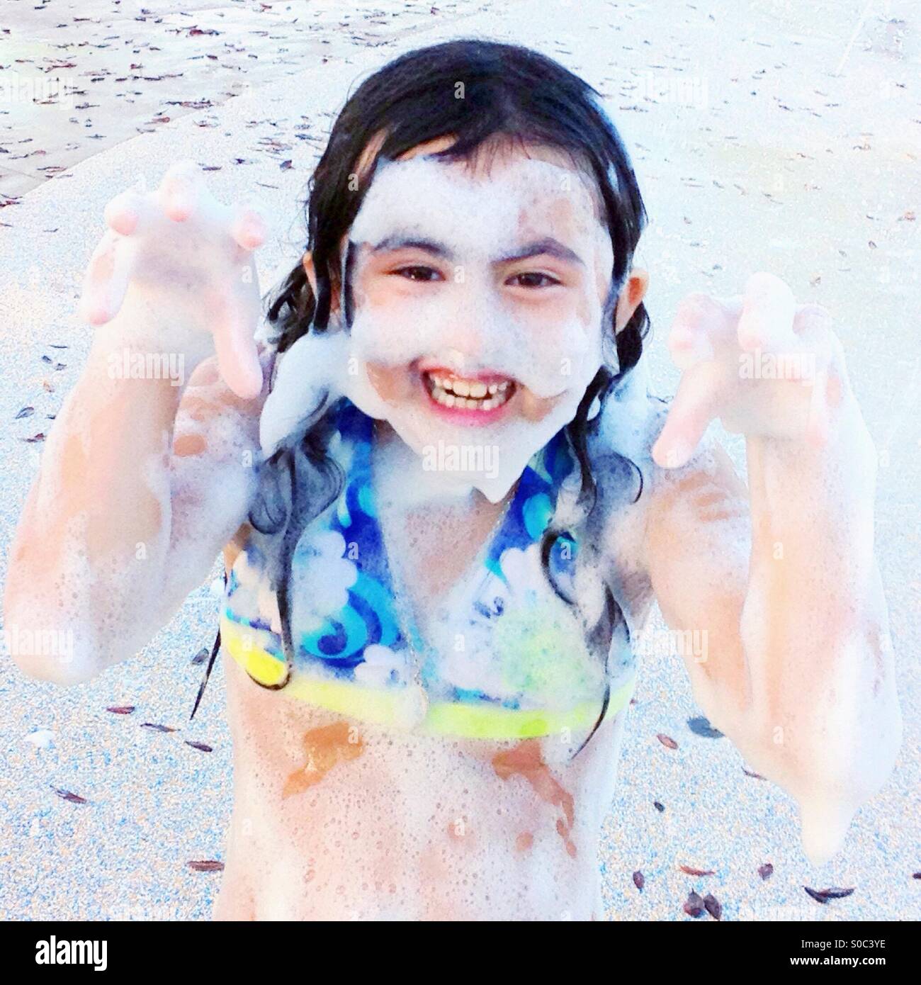 Little girl covered in bubbles at a water park acting scary Stock Photo