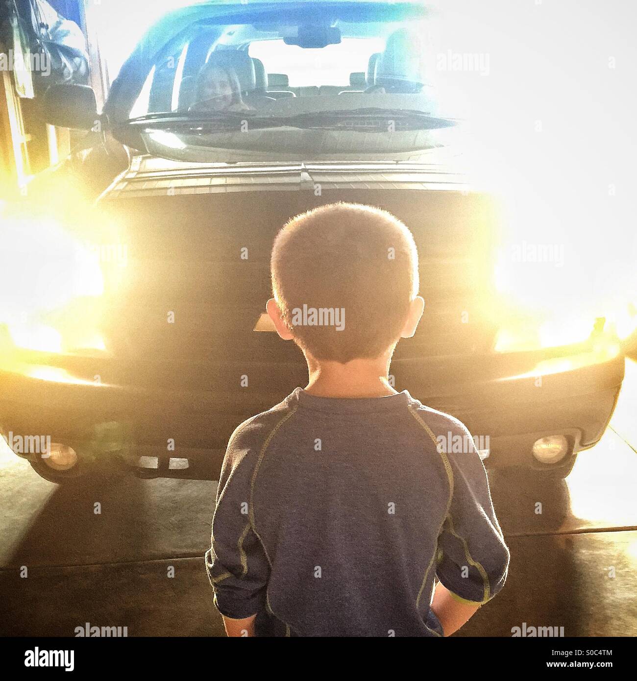 A young boy stares at the headlights of an oncoming vehicle Stock Photo
