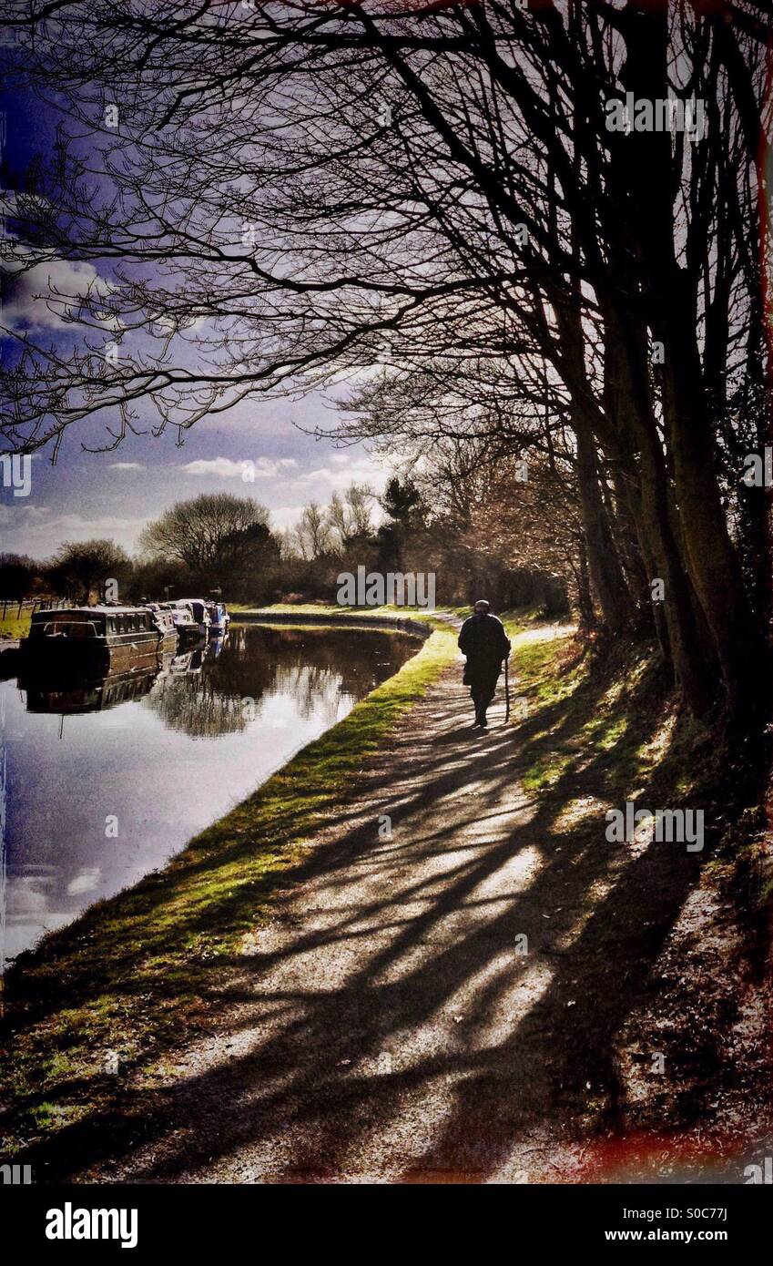 Man with walking stick walking along canal tow path - Smartphone Captured Stock Image