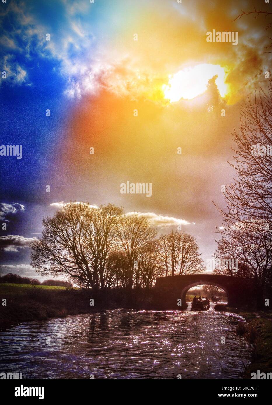 Narrow boats going under stone bridge backlit by sun - Smartphone Captured Stock Image