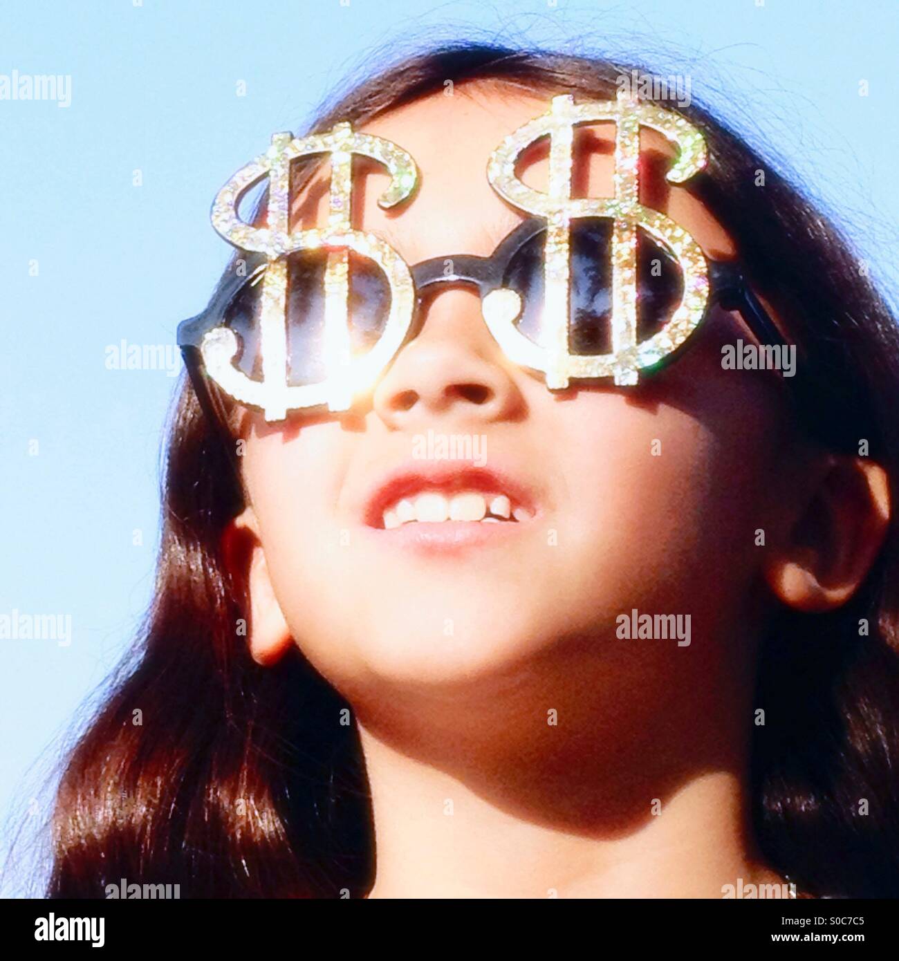 Little girl wearing glasses shaped like dollar signs. Stock Photo