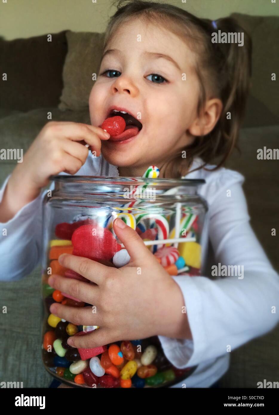 Girl holding candy jar and licking a sucker Stock Photo