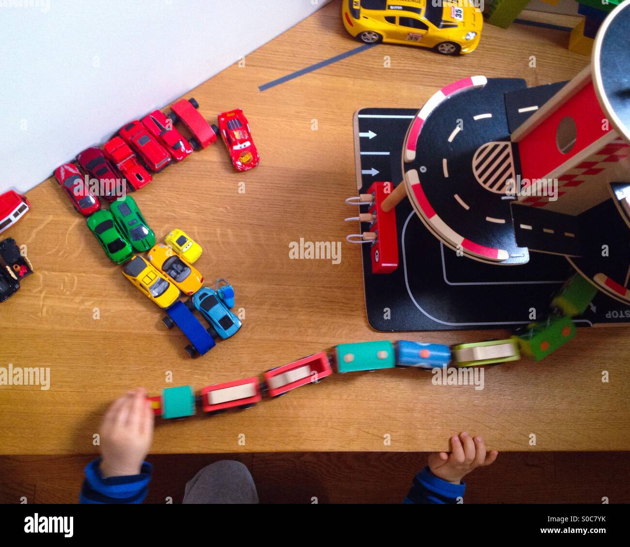 Toddler boy playing with toys like cars, train, trucks, garage, streetcar and racecars Stock Photo