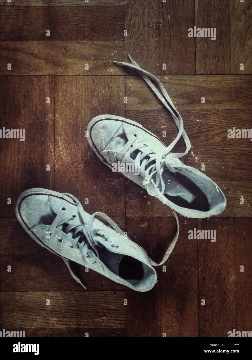 White trainers or sneakers in a wooden floor shot from above with grunge effect. - Smartphone Captured Stock Image