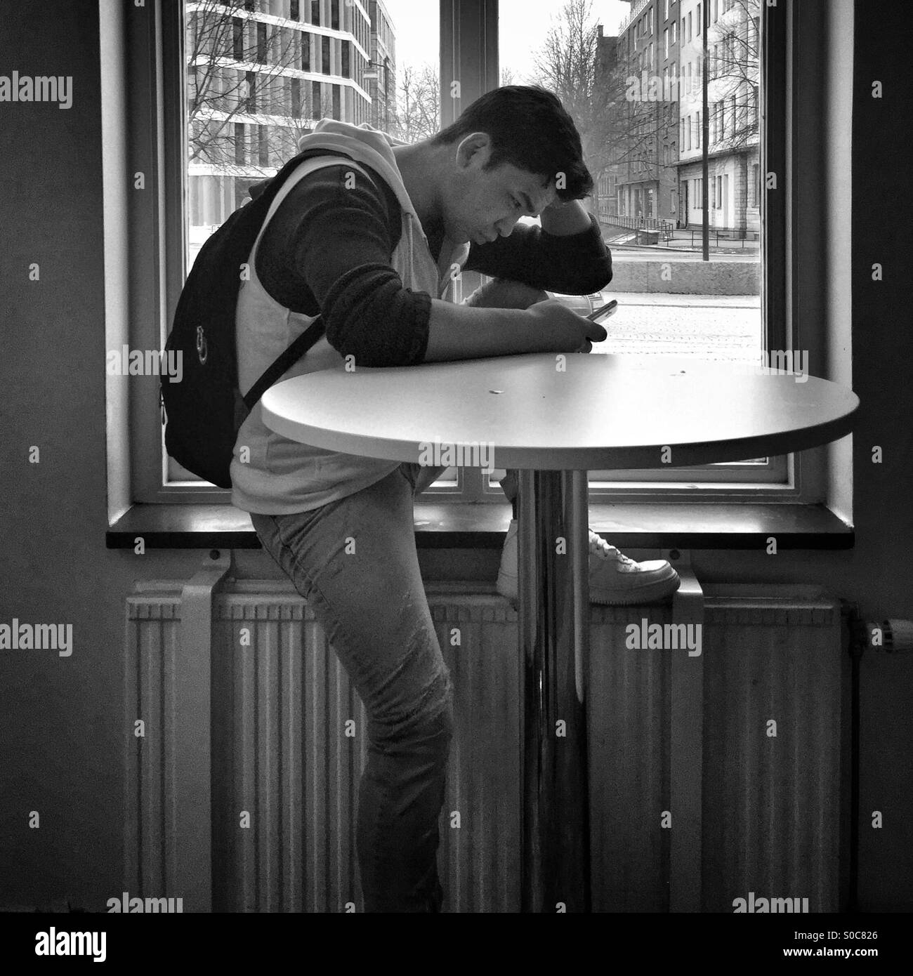 Man and his mobilephone at the window Stock Photo