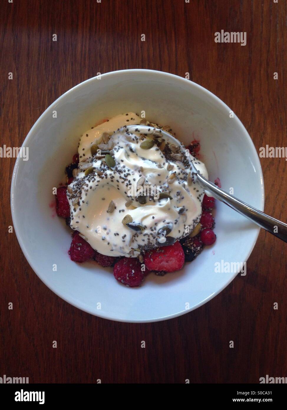Healthy breakfast of yogurt with mixed berries and chia seeds in a white bowl on a rustic wooden table: Phillip Roberts - Smartphone Captured Stock Image