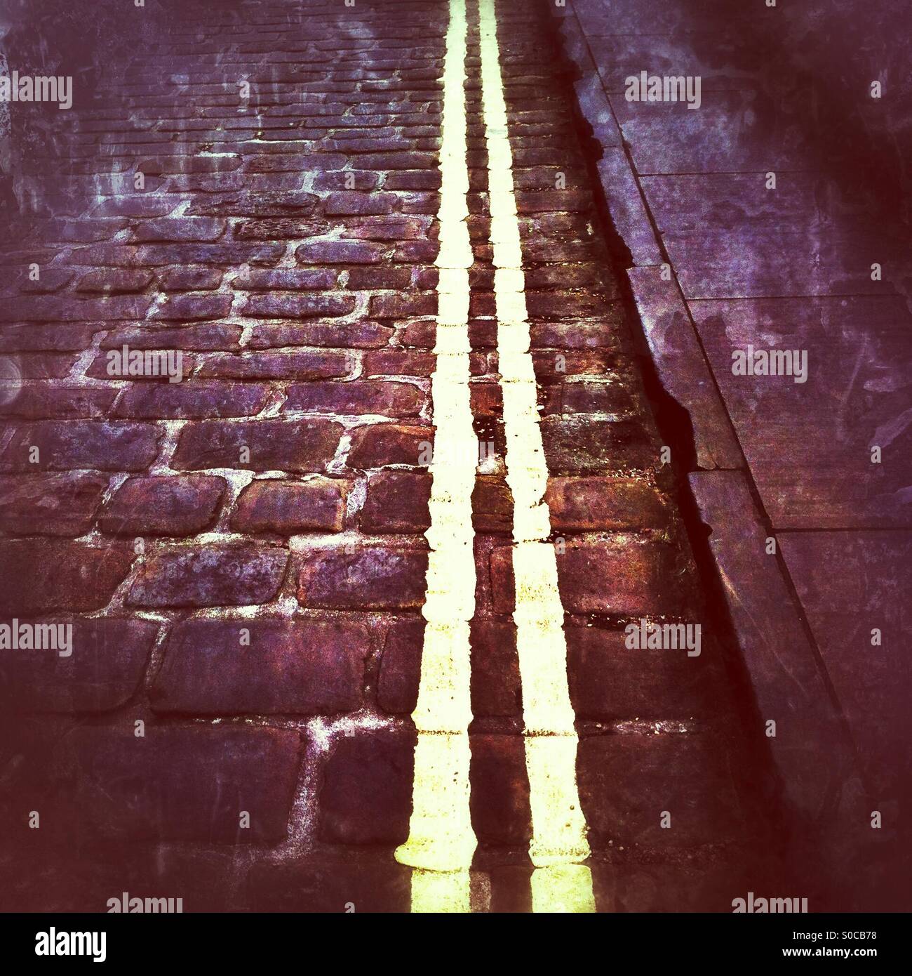 Double yellow lines painted on cobbled street England UK - Smartphone Captured Stock Image