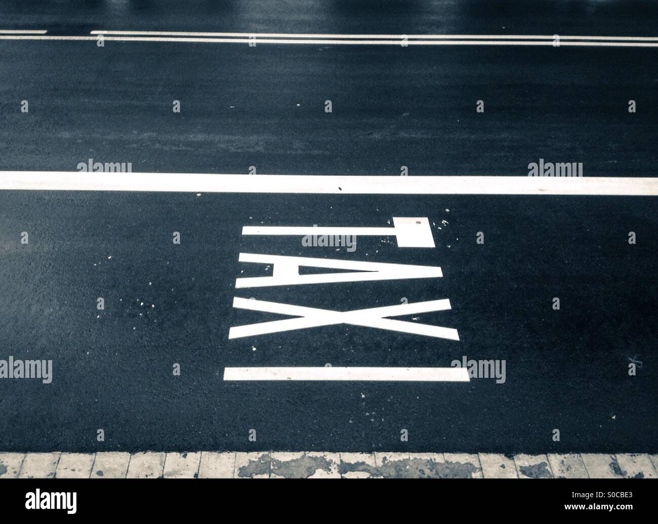 Taxi sign painted on wet asphalt in Barcelona, Catalonia - Smartphone Captured Stock Image