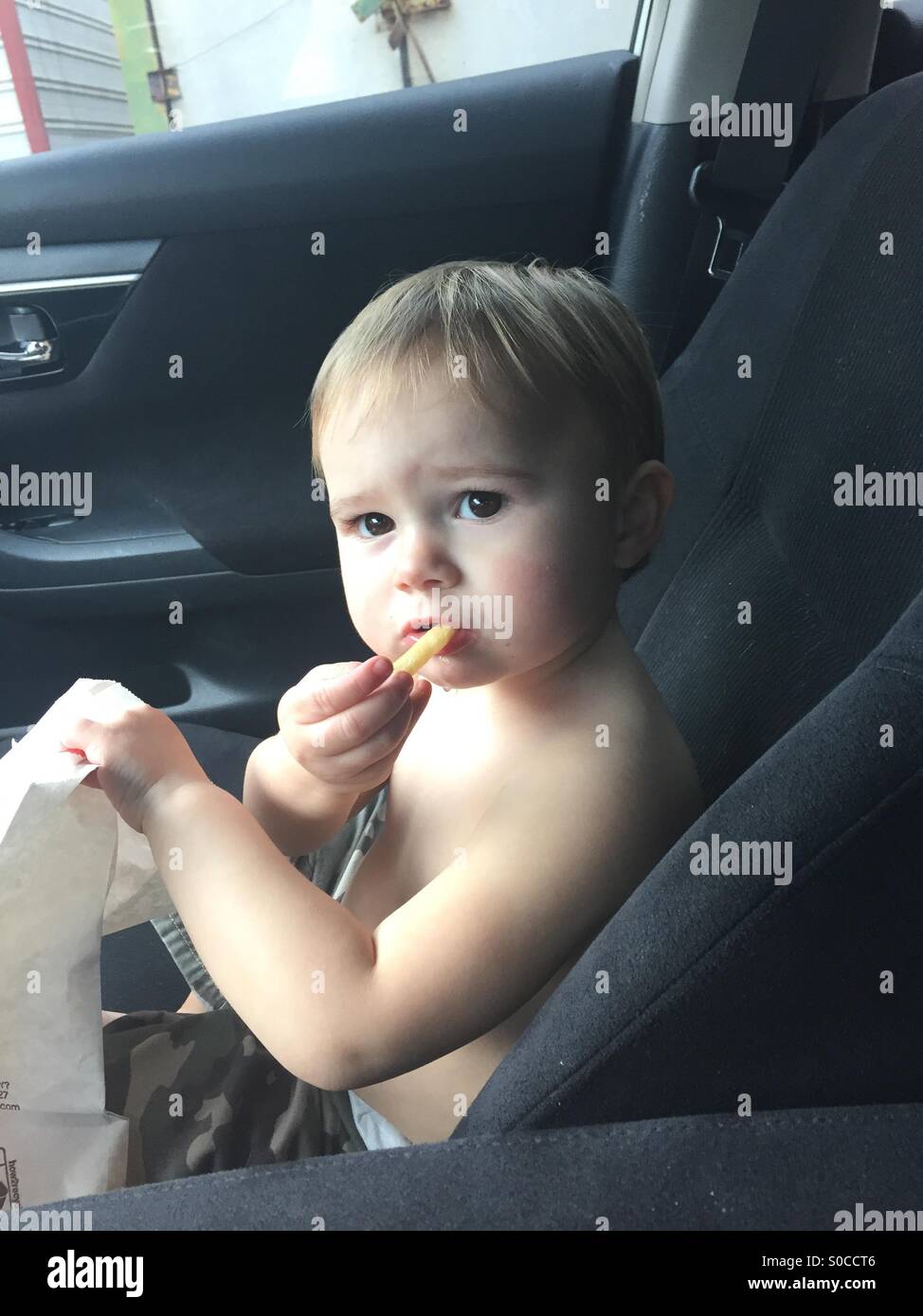 Baby eating fries in car Stock Photo Alamy