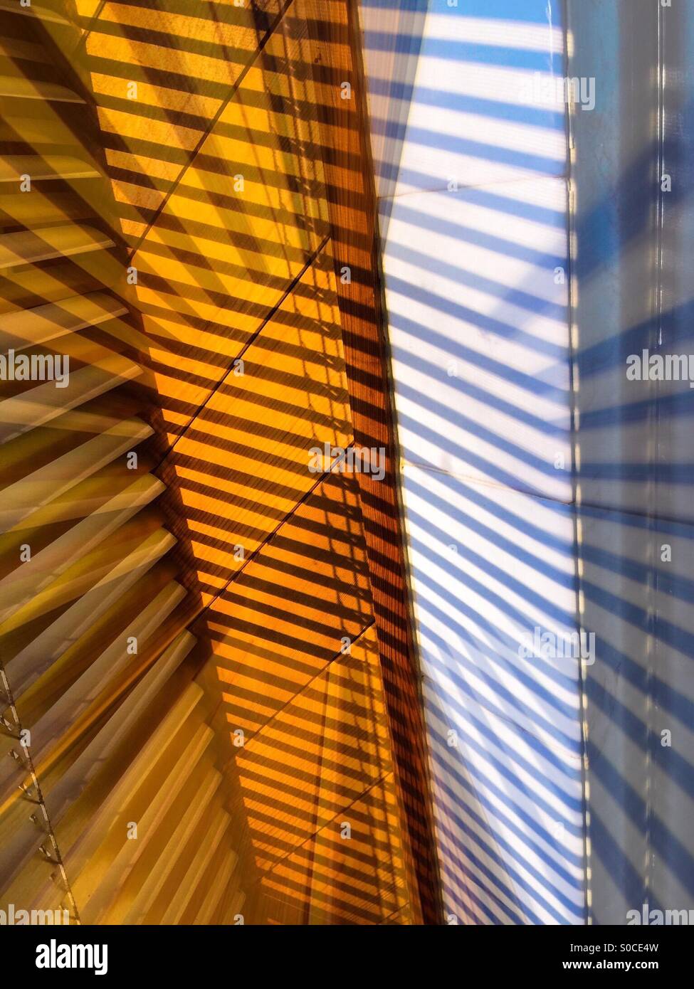 Streaks. Crisscrossing shafts of light in an alcove with many Venetian blinds.  Geometric pattern. - Smartphone Captured Stock Image
