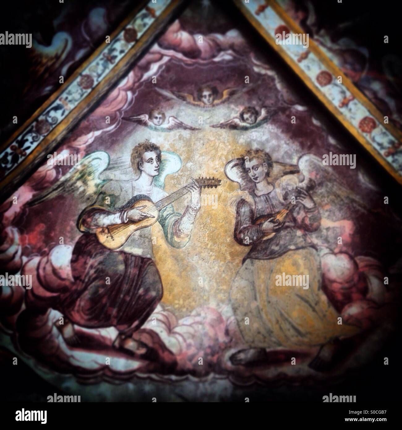 A fresco mural painting of angels playing the guitar and the laude decorate San Sebastian chapel in Alvito, Portugal - Smartphone Captured Stock Image