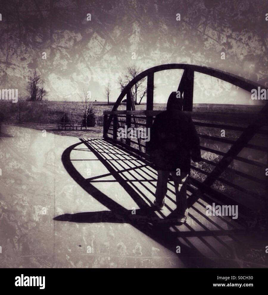 A lady with hooded jacket walking across a bridge (1). - Smartphone Captured Stock Image