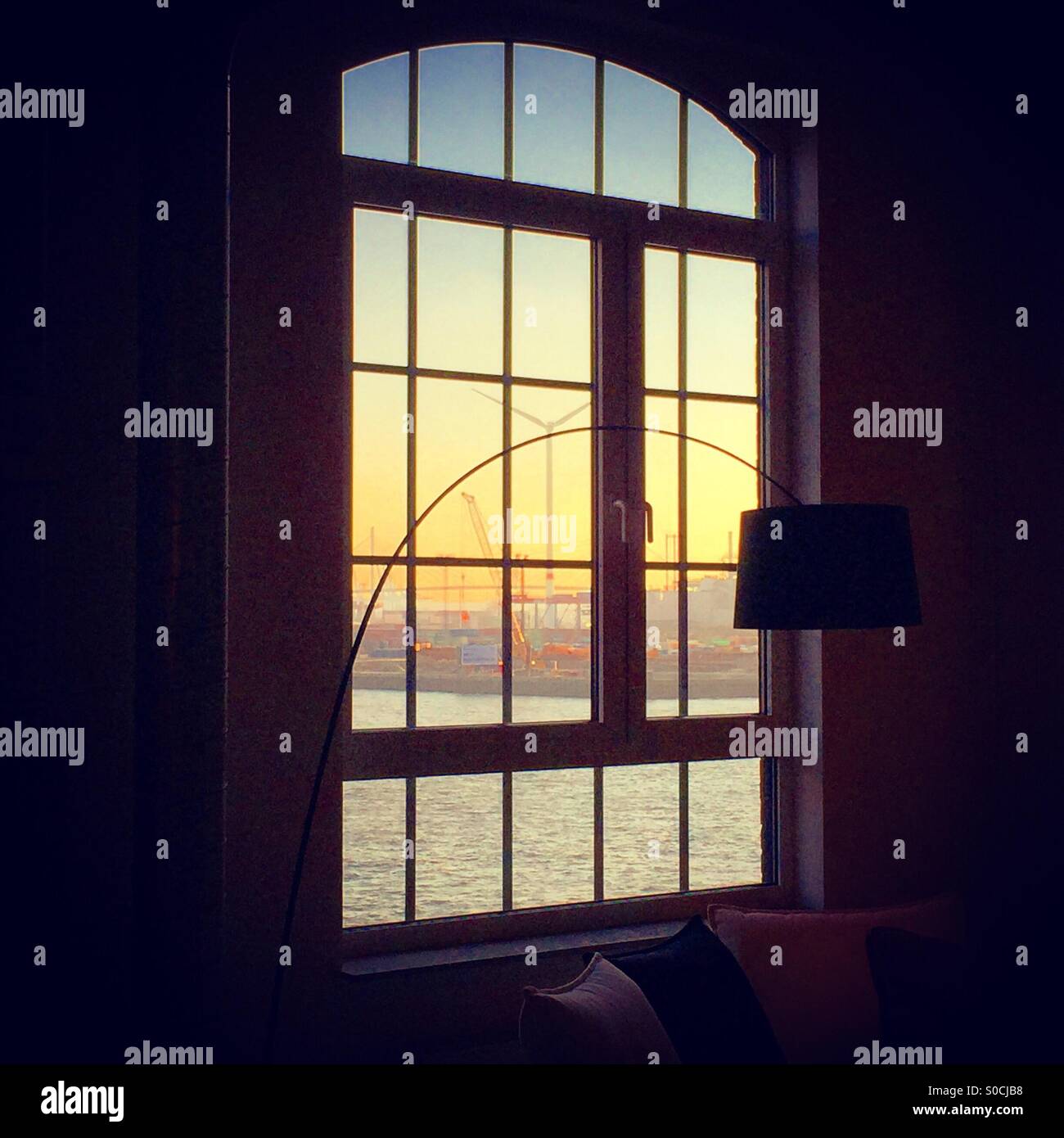 Sunset through a window over Hamburg harbour with modern lamp Stock Photo