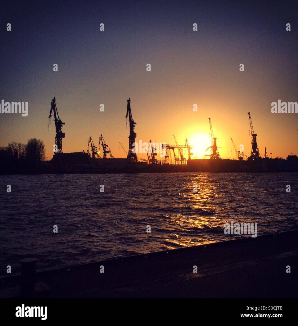 Hamburg harbour at sunset with the sun reflecting off the river elbe Stock Photo