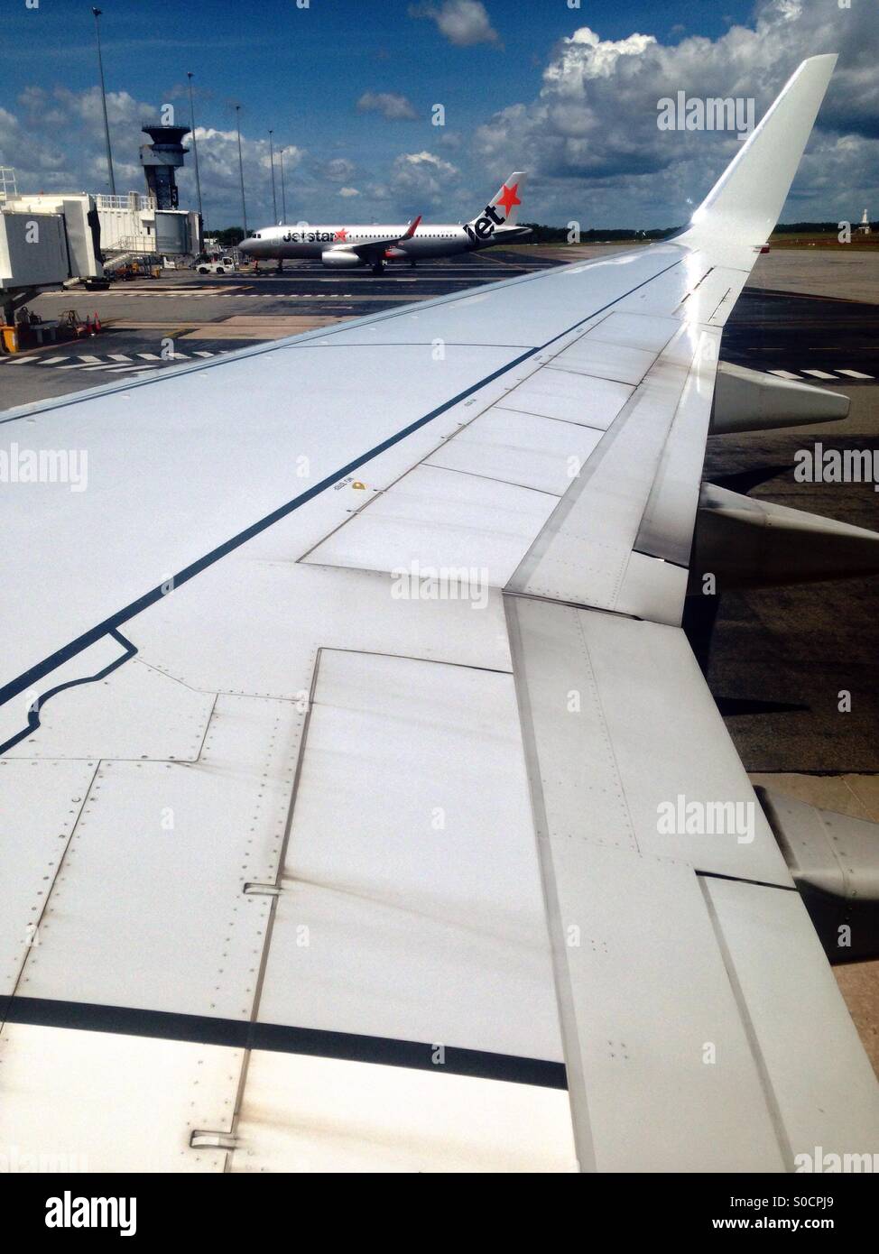 A Jetstar plane, the Australian low cost airline carrier, seen from the window of another airplane at the Darwin International Airport. Darwin, Northern Territory, Australia. Stock Photo
