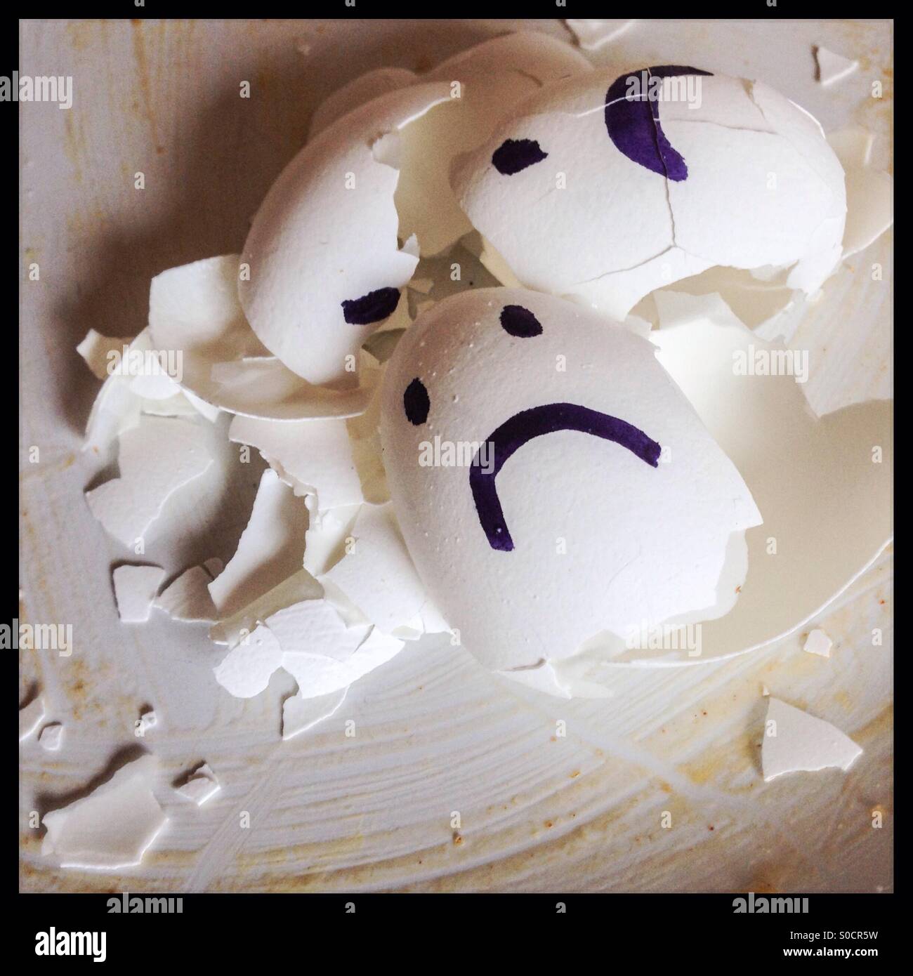 Broken Eggshells with sad faces Stock Photo
