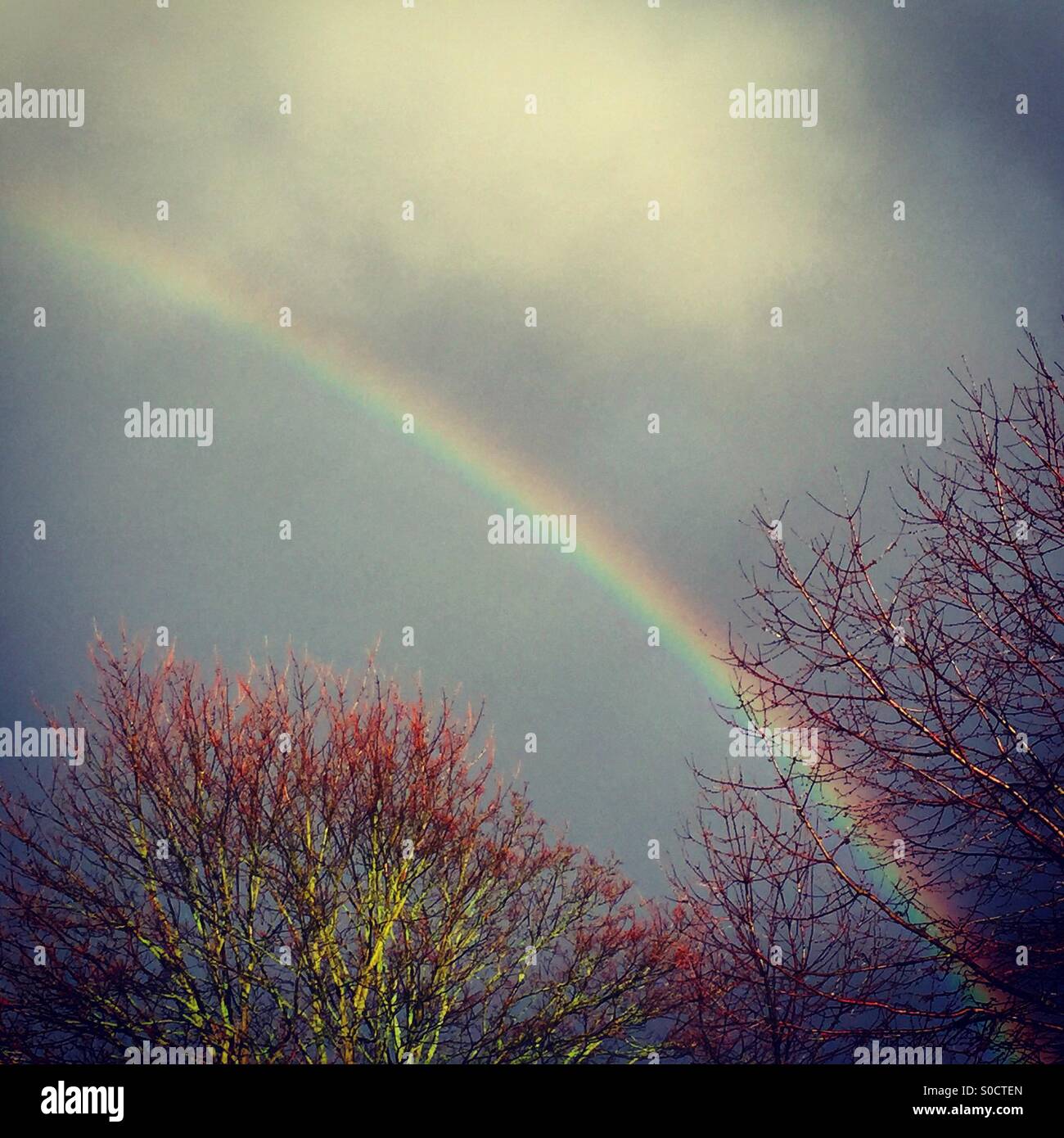 Bright rainbow in front of dark storm clouds Stock Photo
