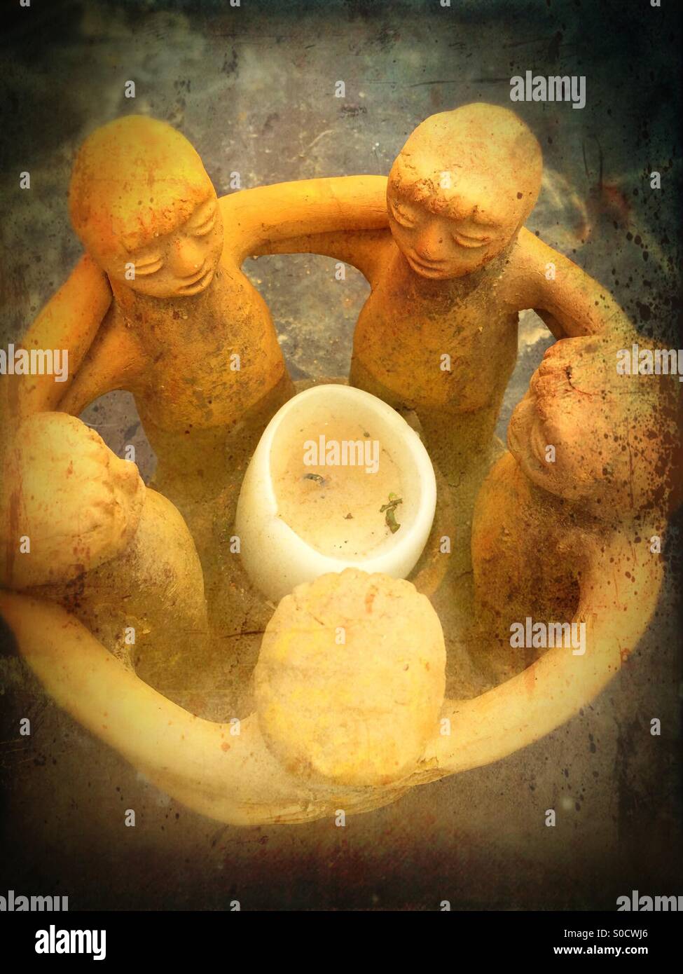 Clay sculpture of 5 figures holding arms around a candle - Smartphone Captured Stock Image