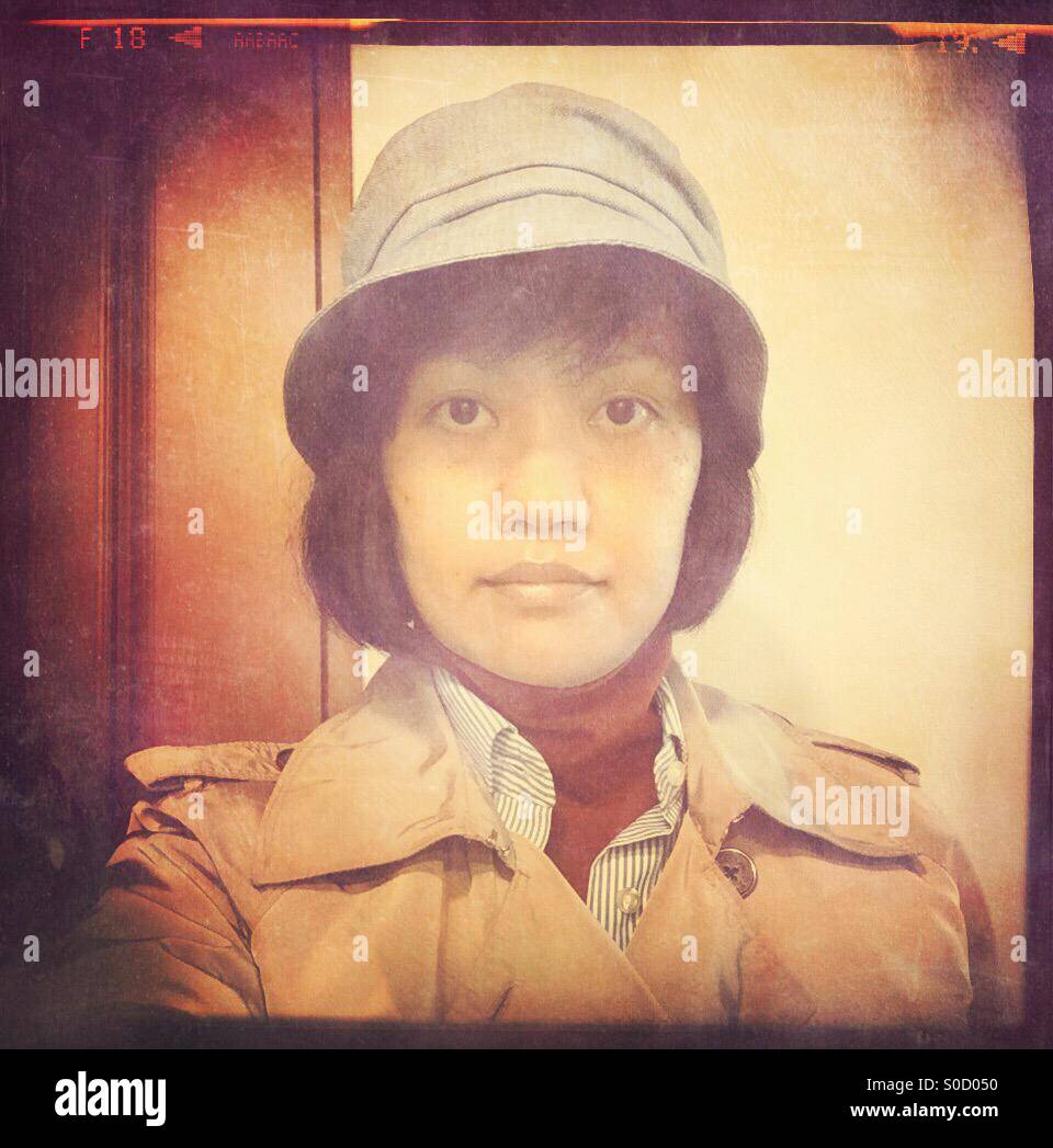 Asian woman selfie, with short bob hair, tan trench coat, red turtleneck, blue striped shirt and hat. Vintage film frame and paper texture overlay. Stock Photo