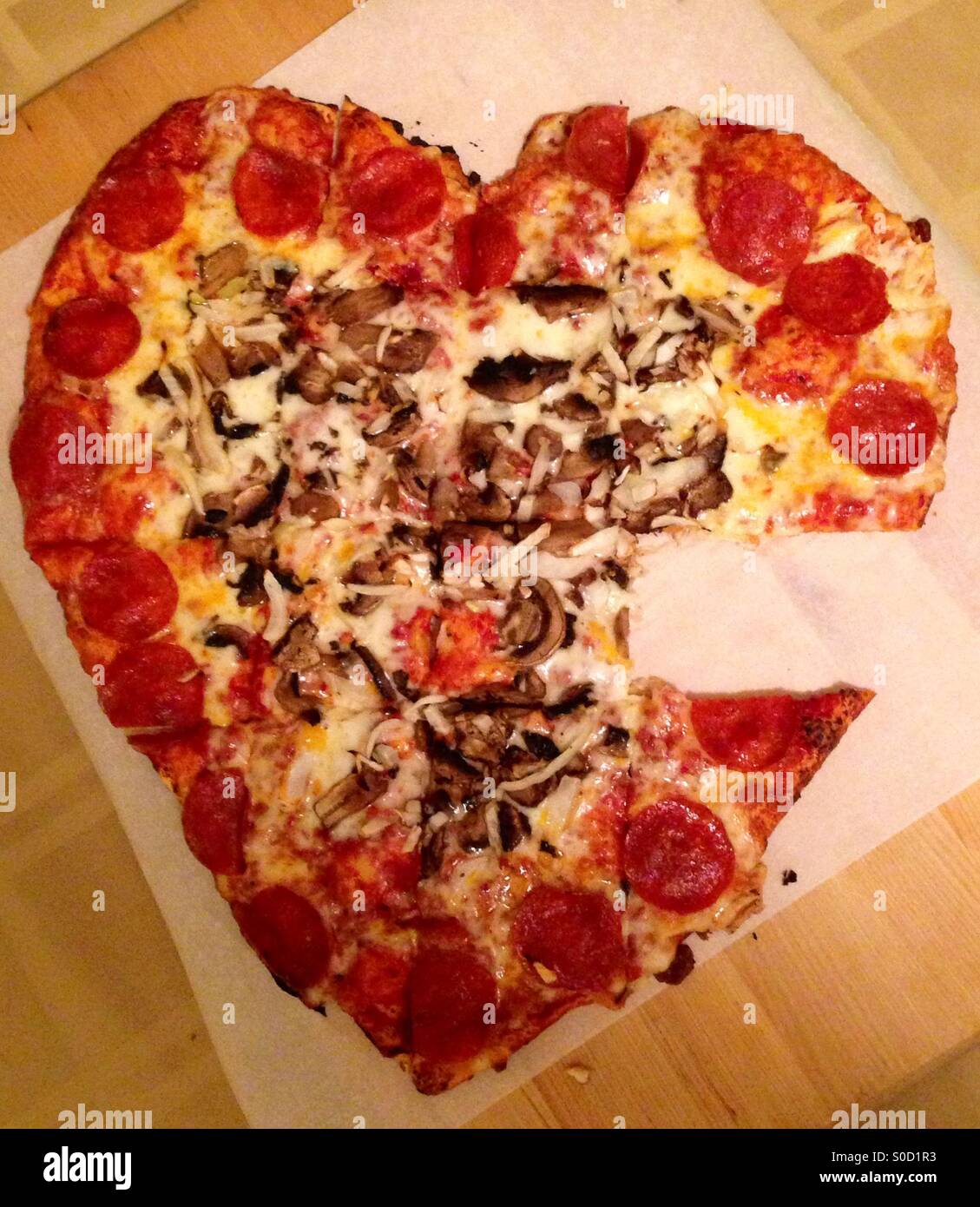 Heart Shaped Pizza for Valentine's Day with a slice missing Stock Photo