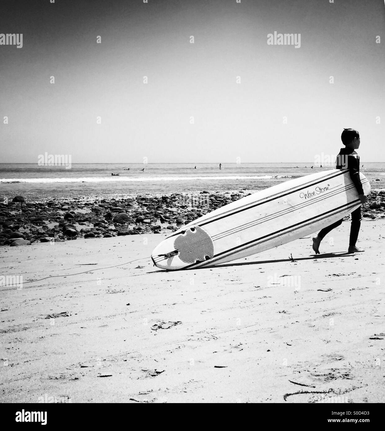 A little boy walks his surfboard up the beach. Malibu, California USA. Stock Photo