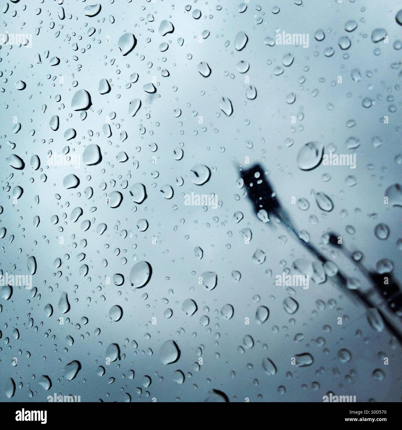 Rain in an urban environment behind car windows at a traffic light stop