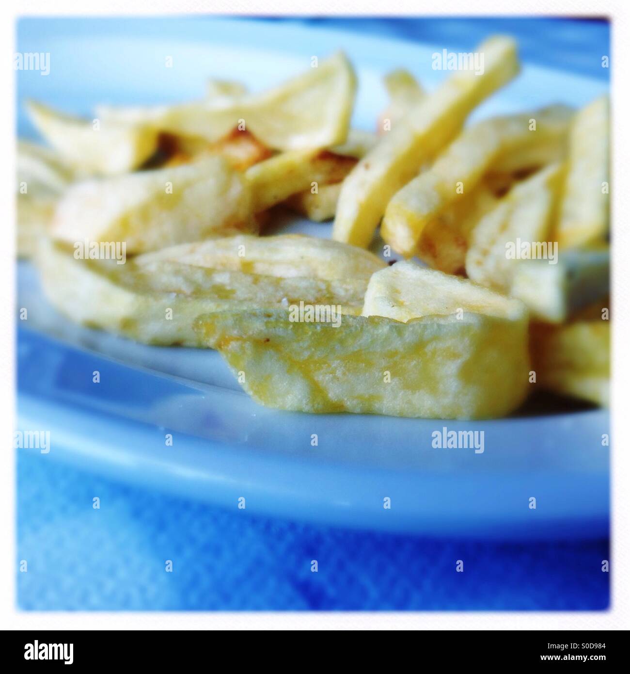 french fries on a white plate standing on a blue tablecloth - Smartphone Captured Stock Image