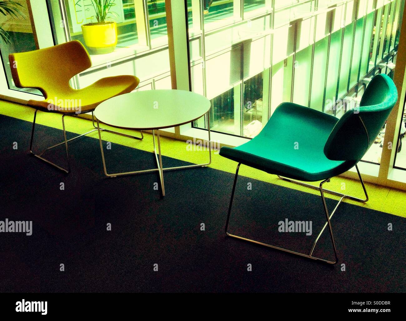 A table and chair in an office space for informal meetings or relaxing. - Smartphone Captured Stock Image