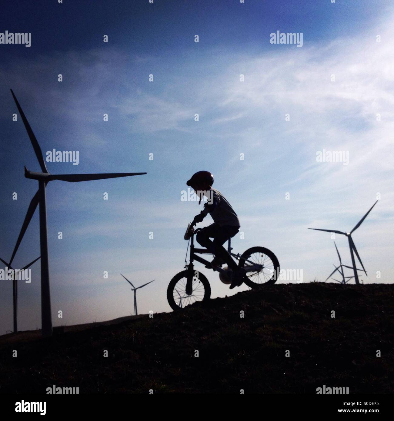 Child cycling amongst wind turbines at Whitelee Wind Farm, Scotland Stock Photo