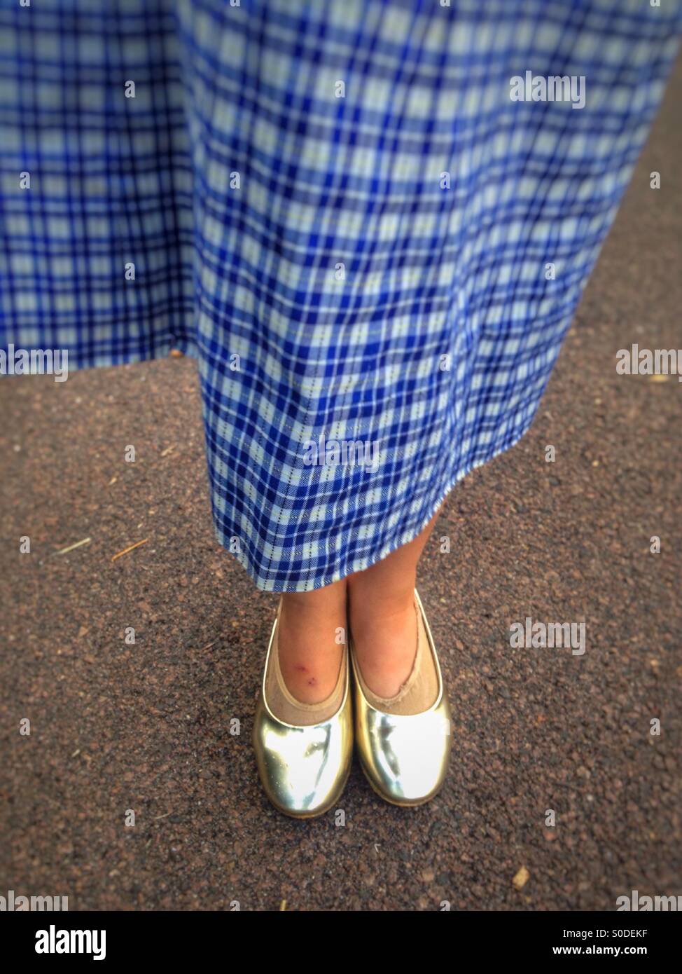 Young girl in school uniform and golden shoes. Stock Photo