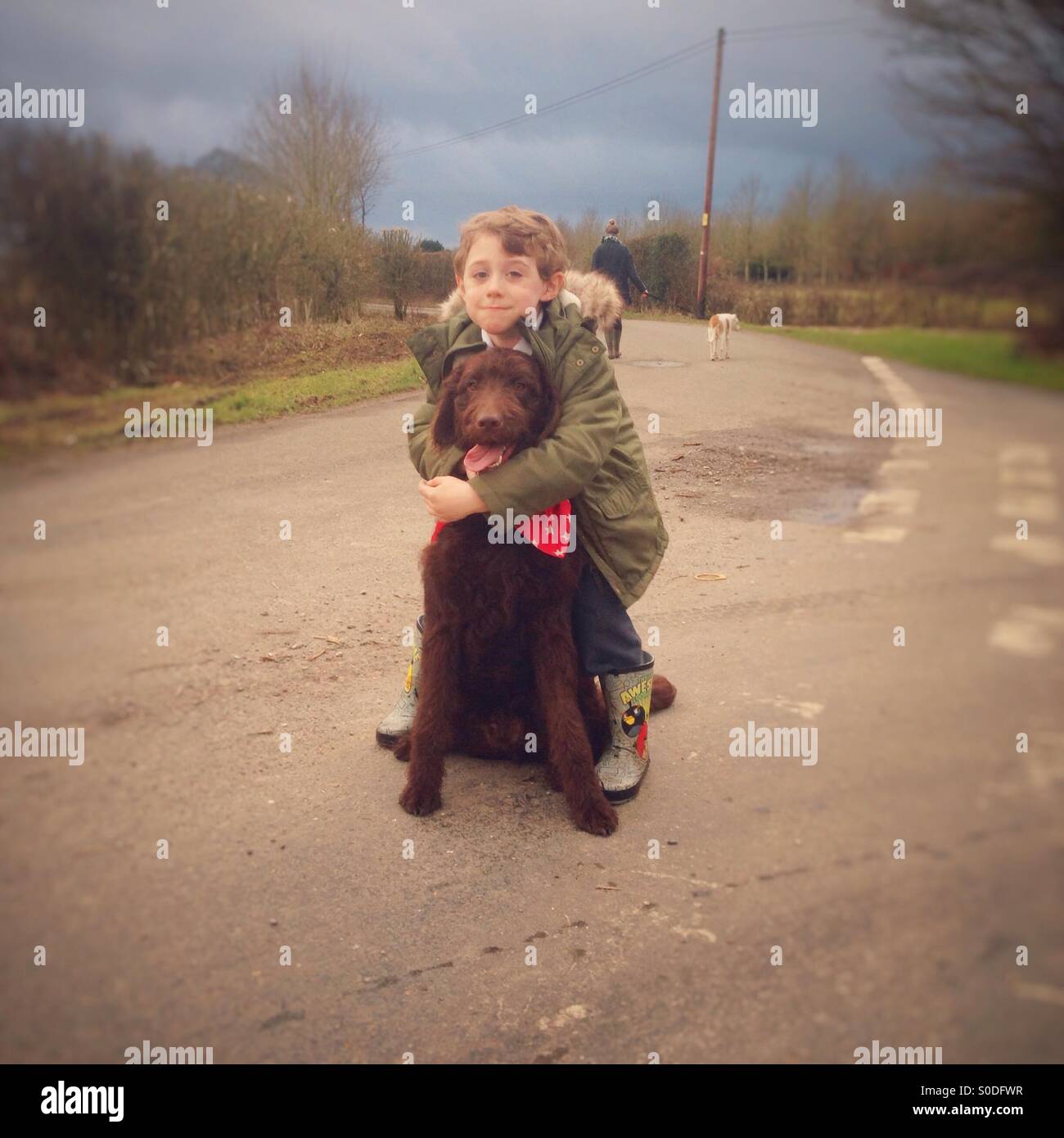 Five year old boy Hugging his pet Labradoodle dog. - Smartphone Captured Stock Image