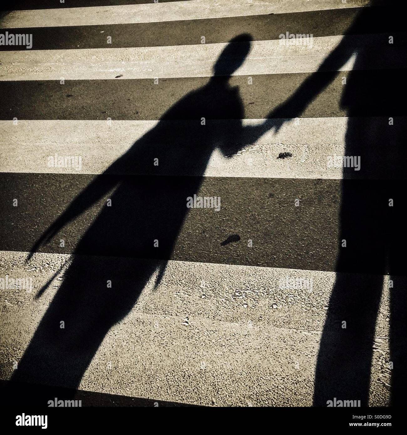 Shadow of a child and his father crossing a pedestrian crossing - Smartphone Captured Stock Image