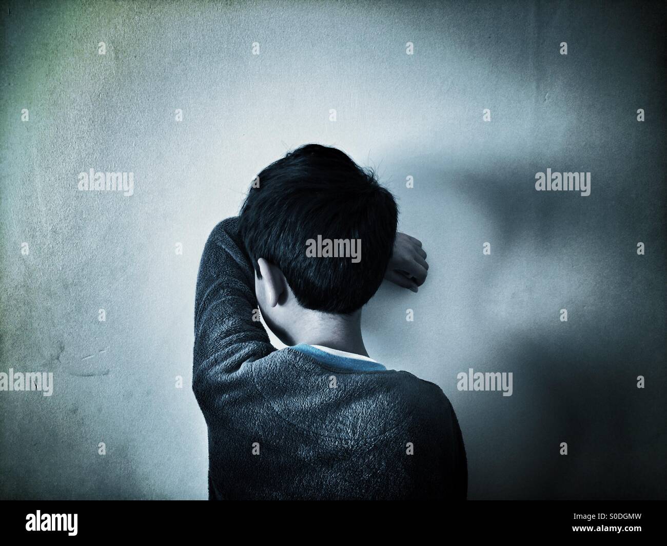 Little boy hiding face against the wall Stock Photo