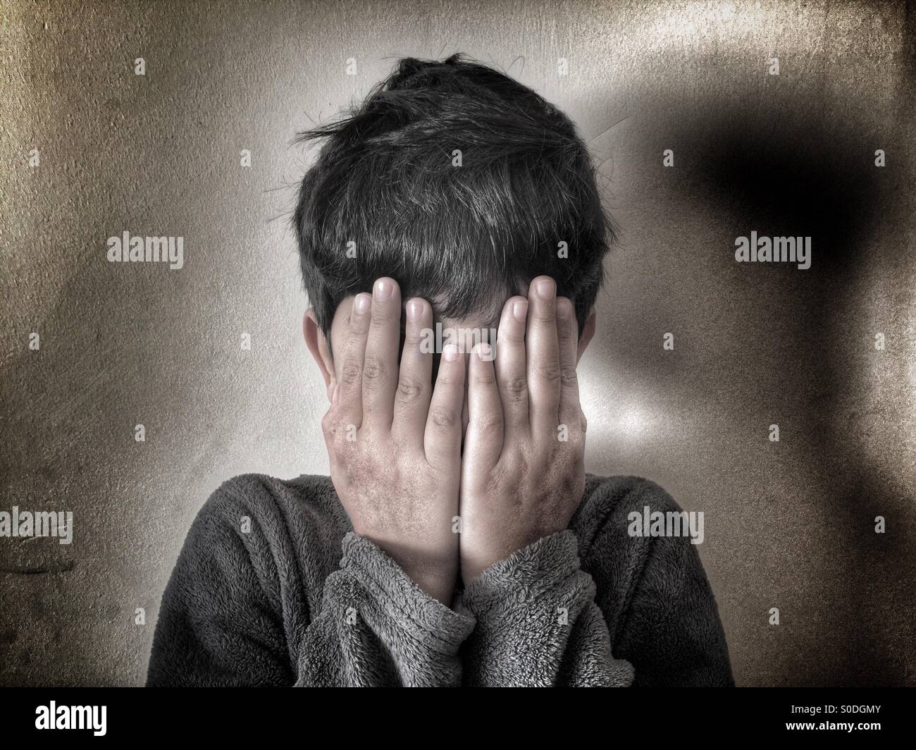 Boy hiding face with hands Stock Photo
