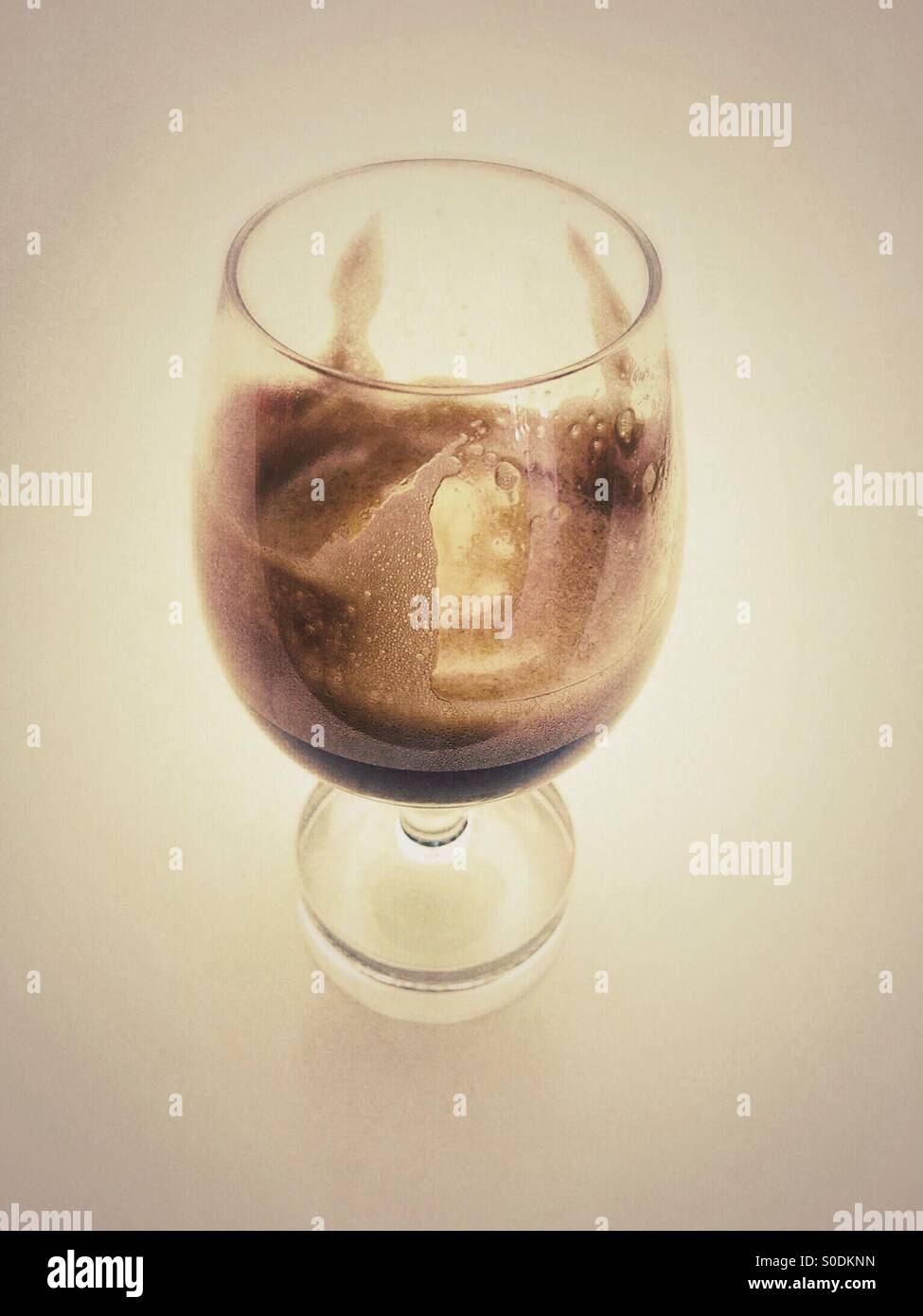 Remains of foamy black espresso coffee which has been served in a wine