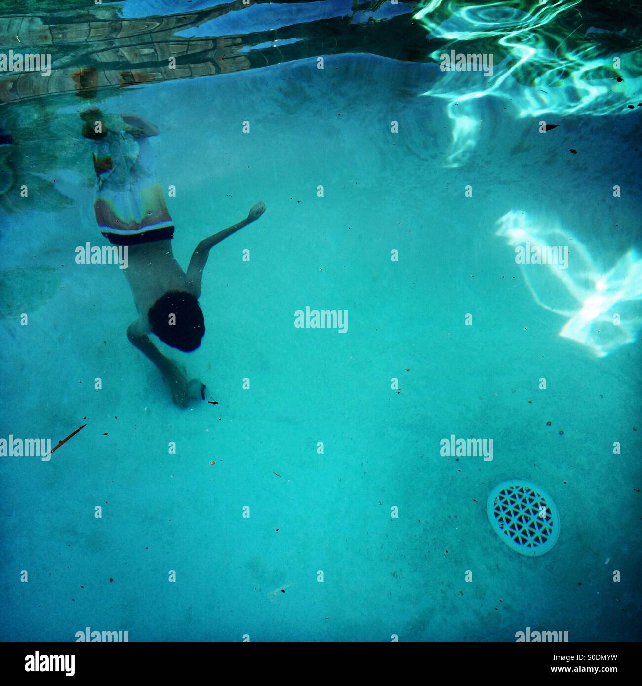 A seven year old boy dives to the bottom of a swimming pool to get his dive mask. Stock Photo